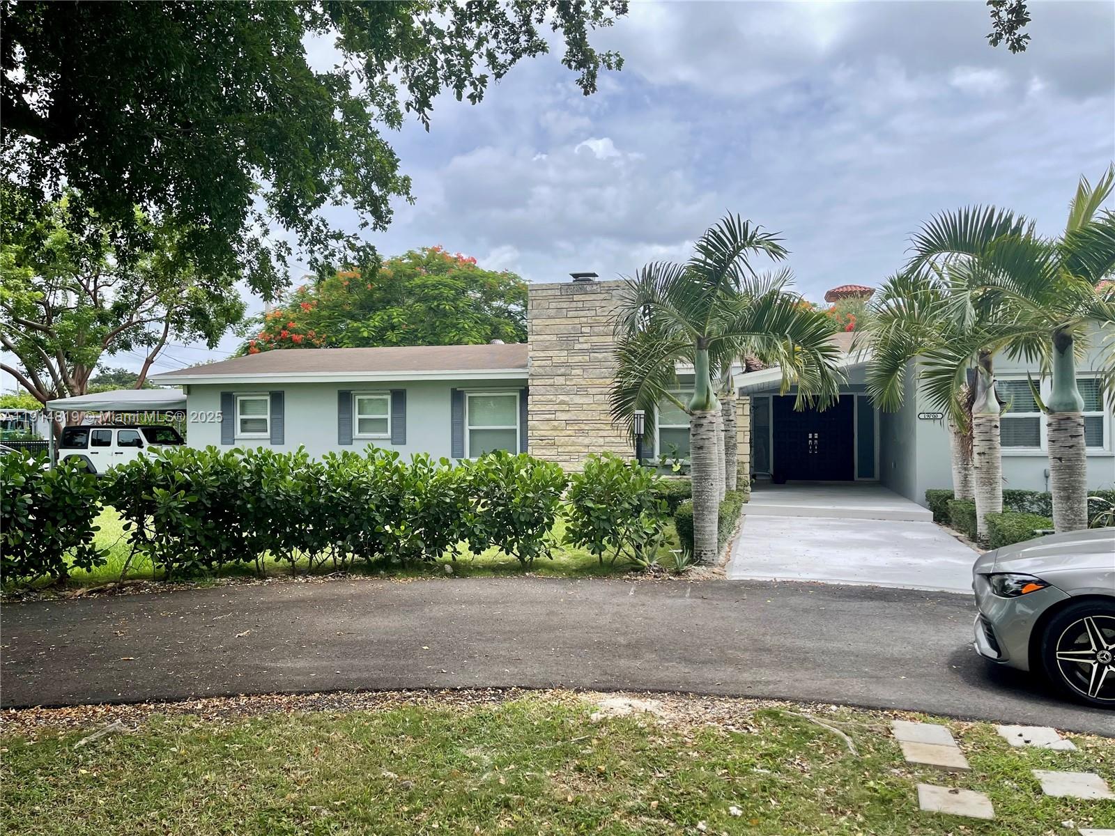a front view of a house with a yard and potted plants