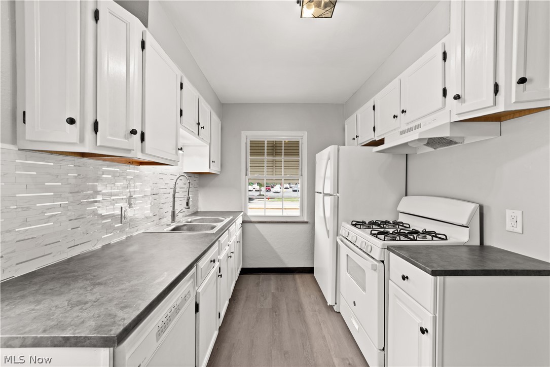 4907 Ridge Road Cleveland, OH 44144 - Photo 2 of 36 Kitchen featuring light hardwood / wood-style flooring, white appliances, sink, decorative backsplash, and white cabinetry