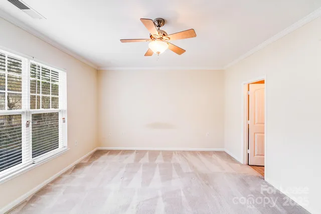 an empty room with window and ceiling fan
