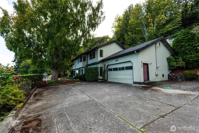 a view of a house with a yard and large trees