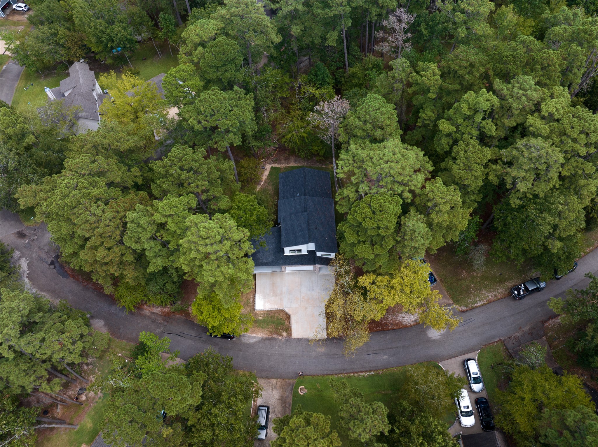 220 North Fairway Loop Coldspring, TX 77331 - Photo 20 of 23 This aerial view showcases a beautiful home in a serene lakeside community, nestled within a lush, forested setting. With a private dock and direct access to the water, the house offers a peaceful and secluded living experience, combining comfort and tranquility in the perfect lakeside retreat.