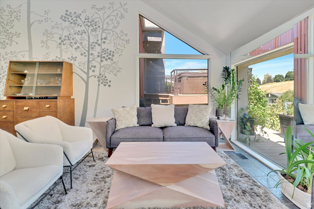 510 Spring Creek Road Providence, UT 84332 - Photo 8 of 97 Expansive windows and sliding glass doors illuminate a contemporary living area featuring a decorative wall mural, tiled flooring, and a terraced outdoor area with a spa