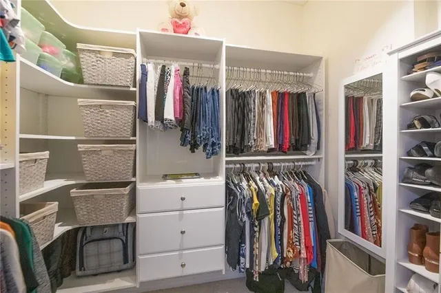 a view of walk in closet with clothes and shoes