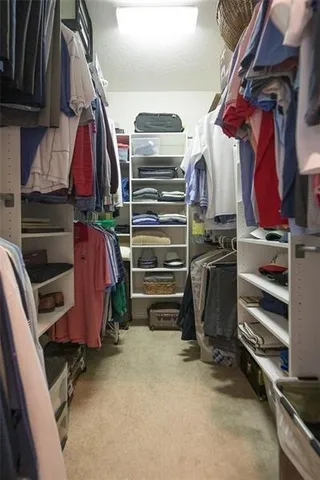a view of walk in closet with clothes and shoes