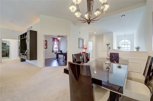 a view of a dining room with furniture a chandelier and kitchen view