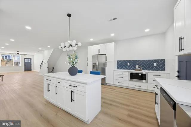 a kitchen with stainless steel appliances kitchen island granite countertop a stove a sink and a refrigerator
