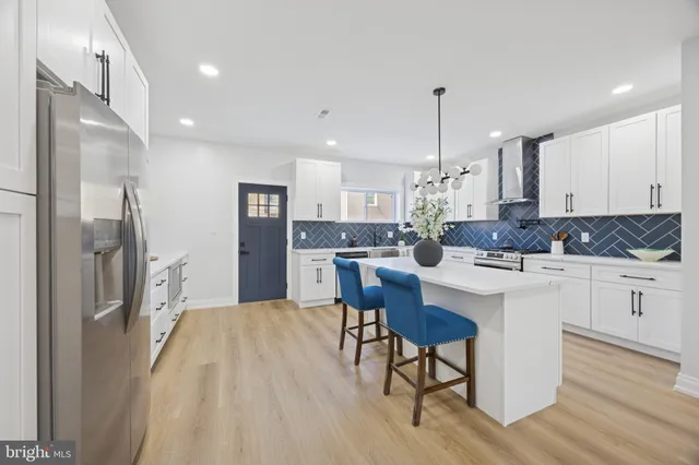 a kitchen with stainless steel appliances kitchen island granite countertop a refrigerator a sink dishwasher a stove and white cabinets with wooden floor