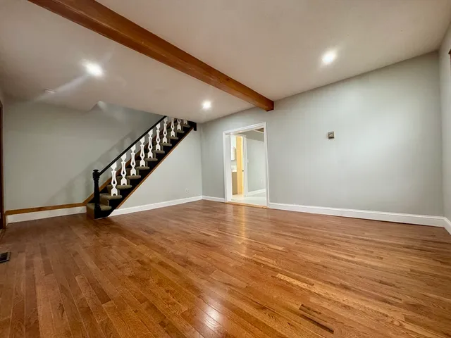 a view of an empty room with wooden floor and stairs