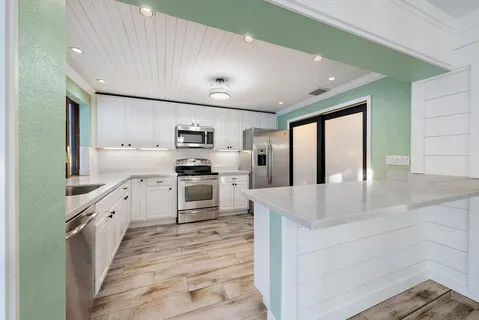 a large white kitchen with cabinets appliances and a sink