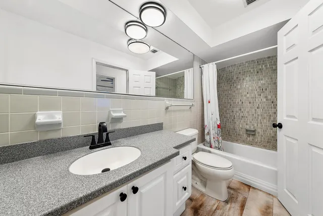 a bathroom with a granite countertop sink a toilet and shower