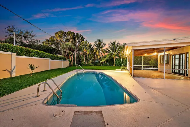 a view of a swimming pool with a yard and potted plants