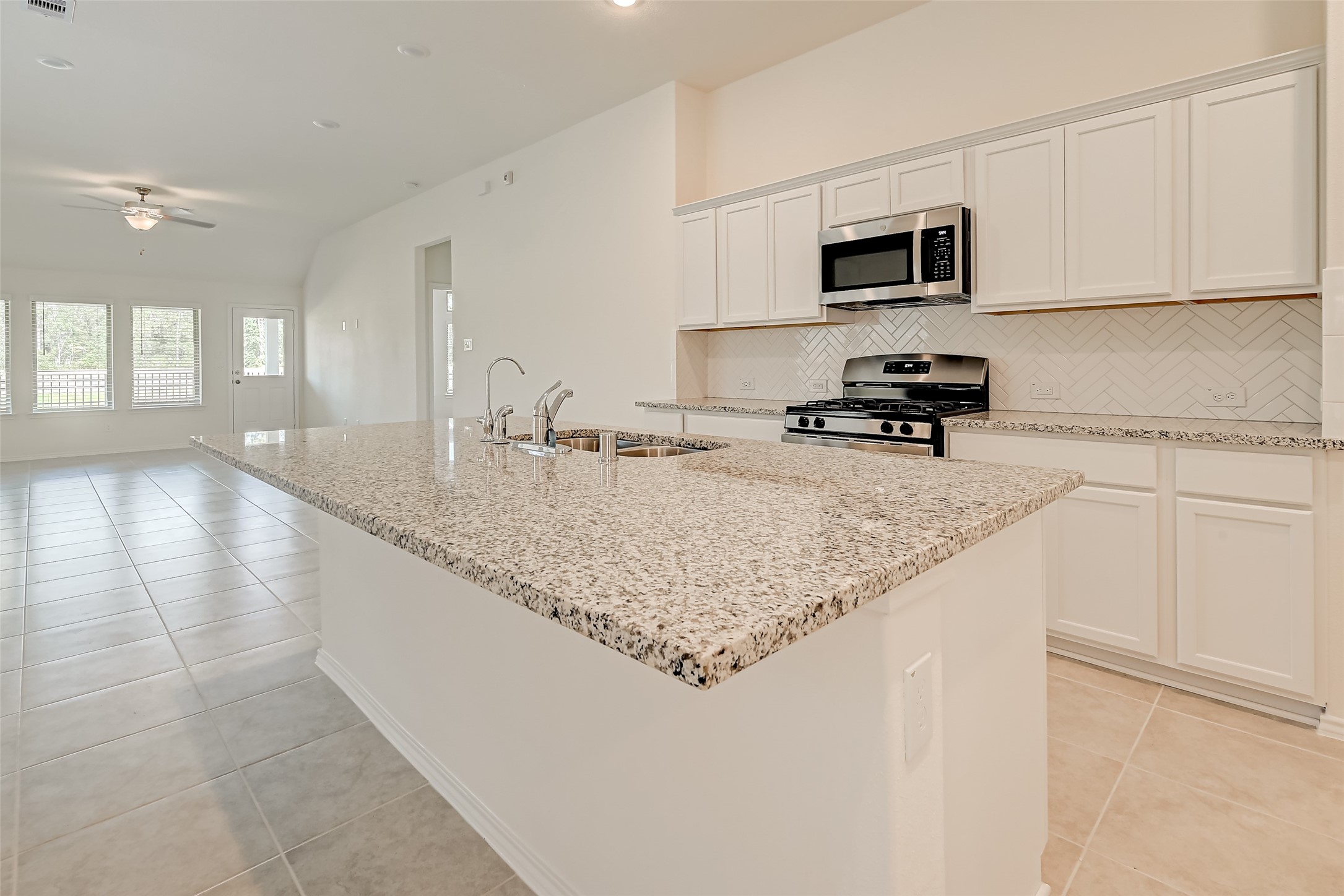 3106 Rising Fir Lane Conroe, TX 77385 - Photo 11 of 32 a kitchen with granite countertop a sink a stove top oven a counter space and cabinets
