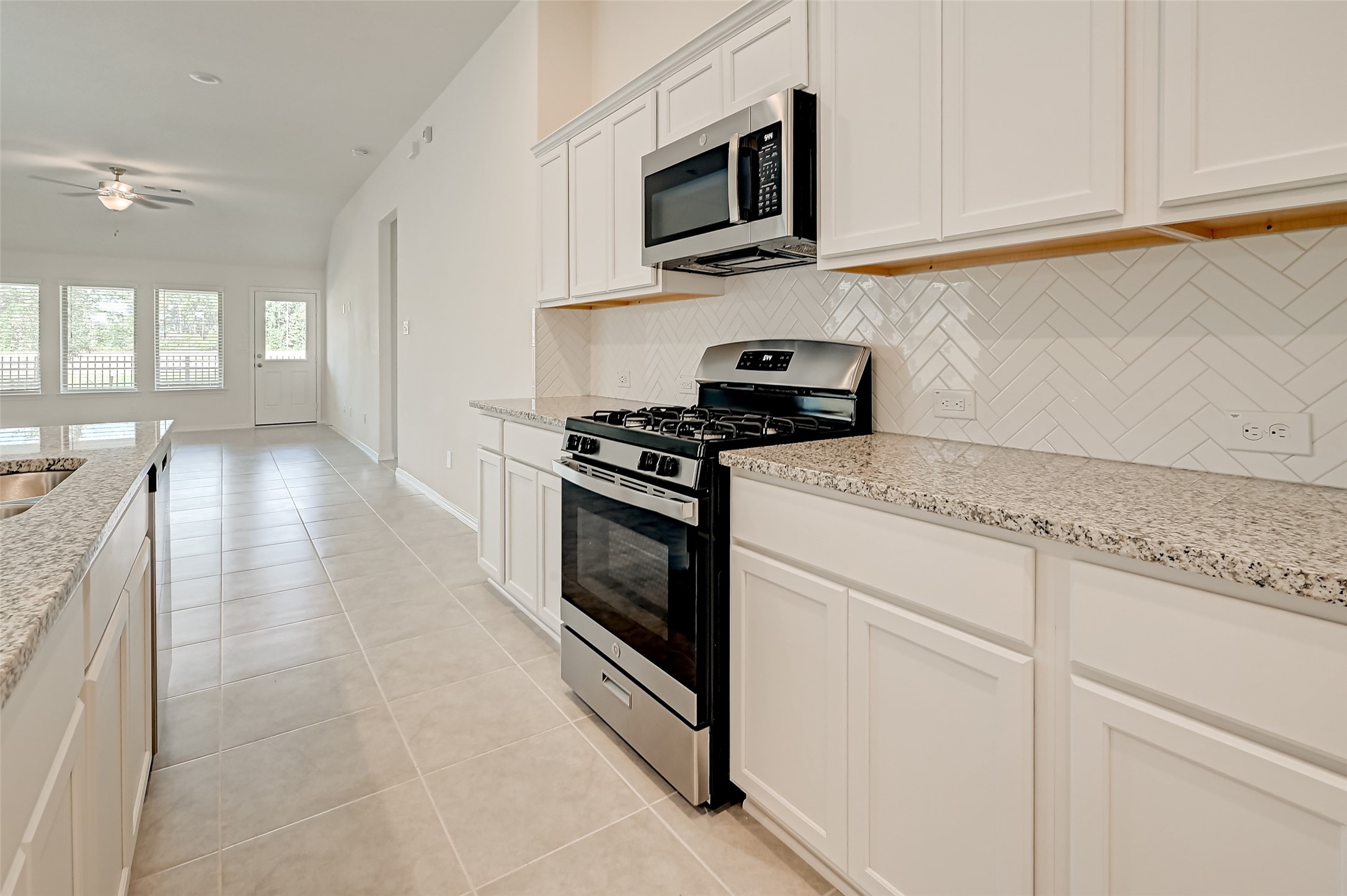 3106 Rising Fir Lane Conroe, TX 77385 - Photo 10 of 32 a kitchen with stainless steel appliances granite countertop a sink a stove and microwave