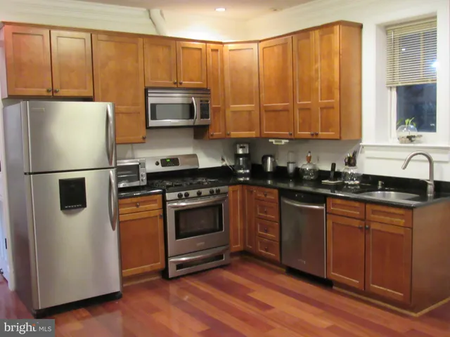 a kitchen with stainless steel appliances granite countertop a stove a sink and a refrigerator