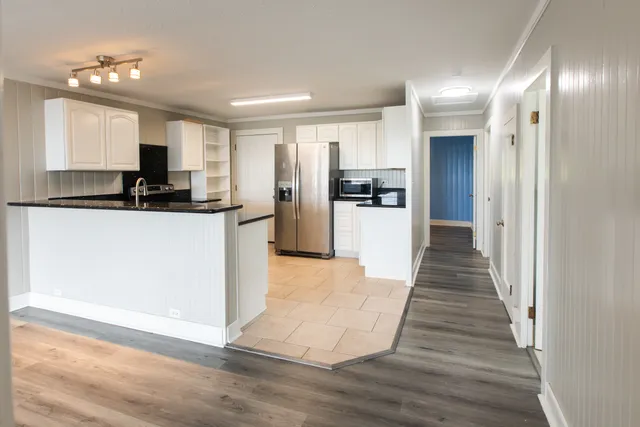 a view of an empty room with kitchen and a window