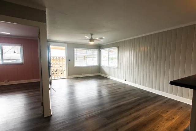 a view of an empty room with wooden floor and a window