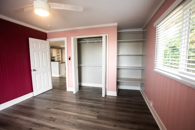 a view of an empty room with wooden floor and a window