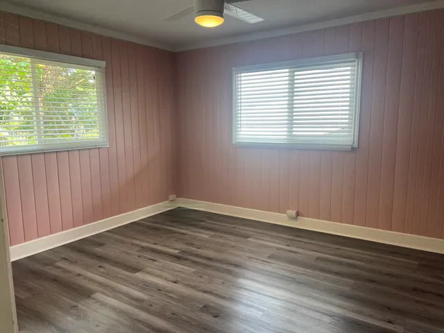 a view of an empty room with window and wooden floor