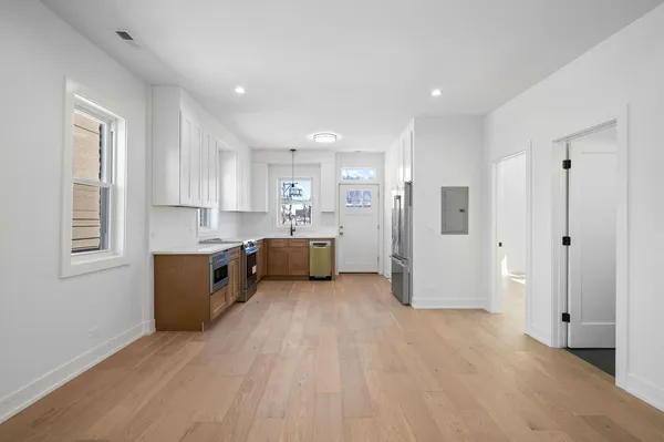 a large white kitchen with stainless steel appliances granite countertop a refrigerator a sink dishwasher and a stove with wooden floor