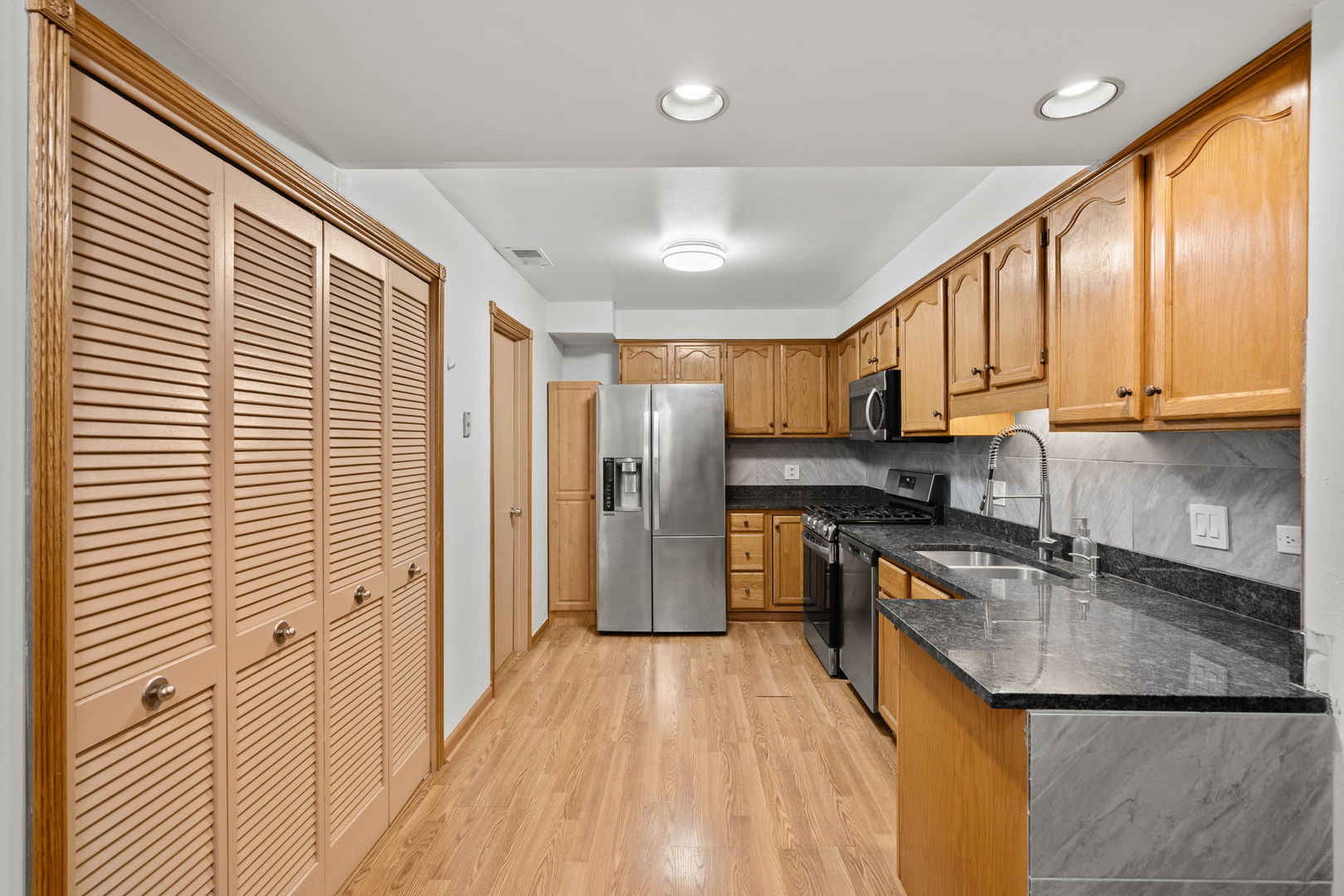 6337 Roosevelt Road, Unit 208 Berwyn, IL 60402 - Photo 4 of 14 a kitchen with stainless steel appliances granite countertop a refrigerator a sink dishwasher a stove and white countertops with wooden floor