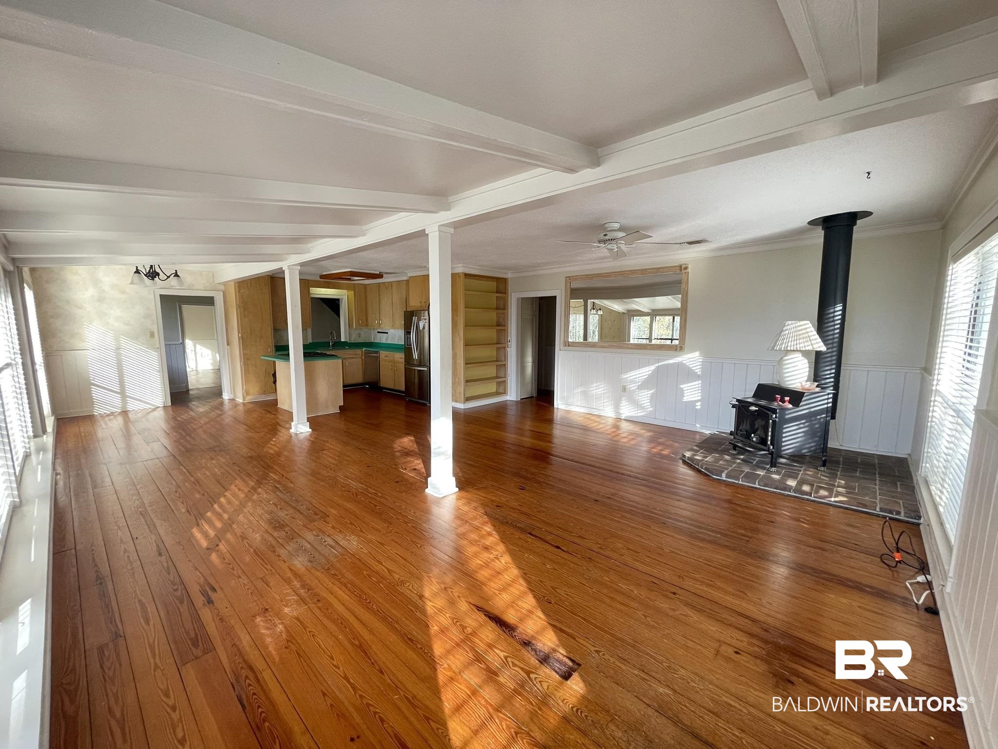 6621 Purvis Road Daphne, AL 36527 - Photo 11 of 59 Unfurnished living room with hardwood / wood-style flooring, crown molding, a wood stove, healthy amount of natural light, and ceiling fan
