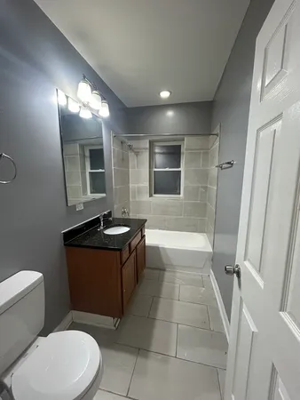 a bathroom with a granite countertop sink toilet mirror and bathtub