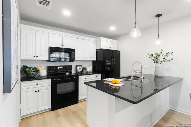 a kitchen with kitchen island granite countertop a sink stainless steel appliances and white cabinets