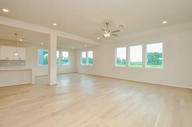 an empty room with windows and ceiling fan