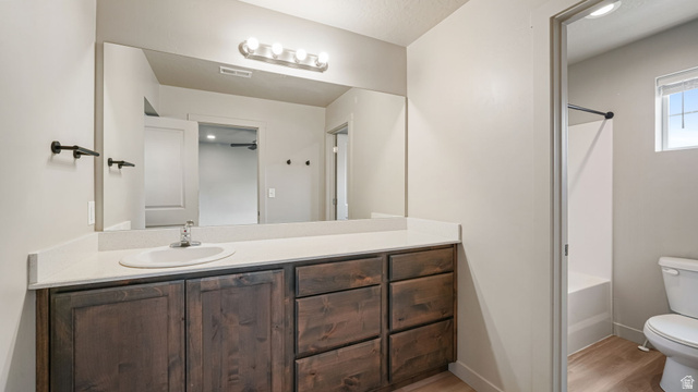1223 East 1775 North Payson, UT 84651 - Photo 33 of 45 Bathroom featuring a long vanity with a light-colored countertop and integrated sink, rich wood-finish cabinetry, a large wall-mounted mirror, and a contemporary four-bulb light fixture