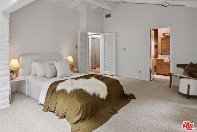 a spacious bedroom with a bed and a tv on the dresser