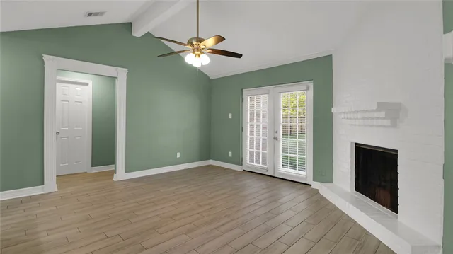 an empty room with wooden floor fan and windows
