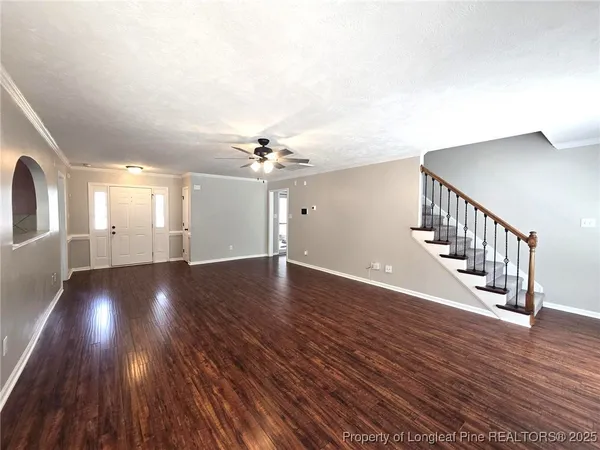 a view of an empty room with wooden floor and staircase
