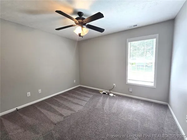 an empty room with a window and a fan