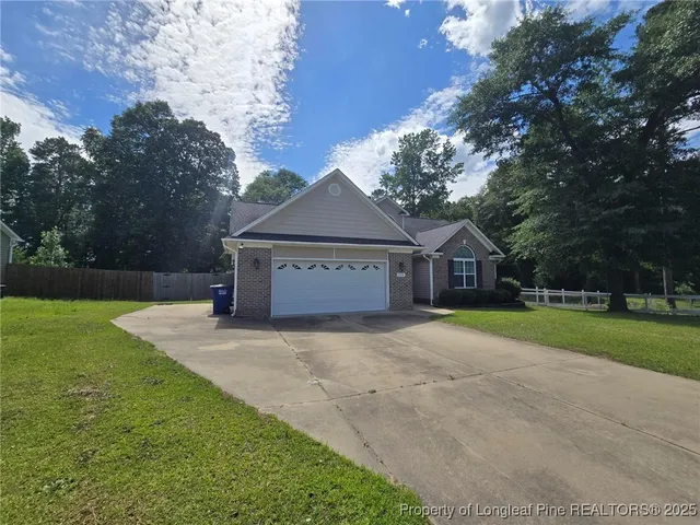 a view of a house with a yard and large tree