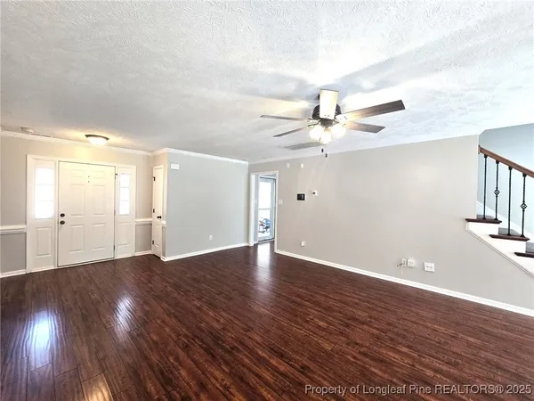 a view of an empty room with wooden floor and a ceiling fan
