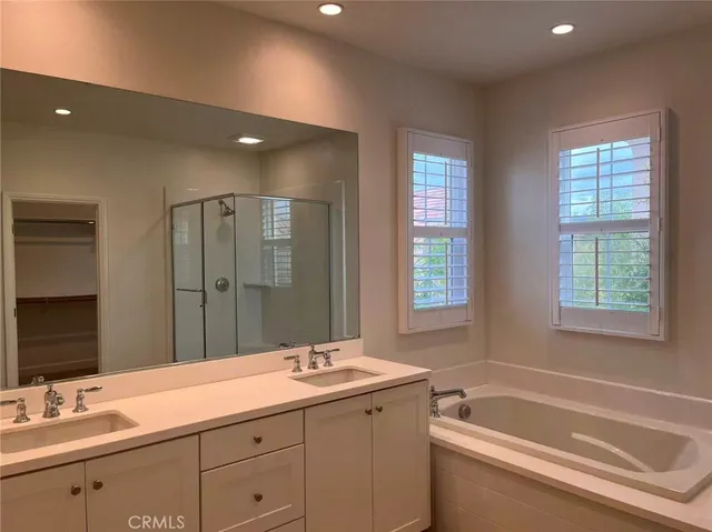 a bathroom with a sink double vanity granite tub shower and a mirror