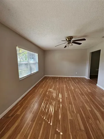a view of a room with wooden floor ceiling fan and windows