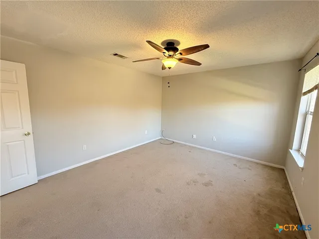 an empty room with a window and a fan