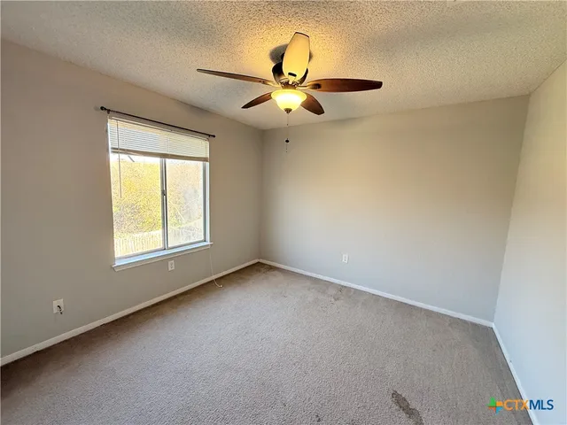 an empty room with a window and a fan