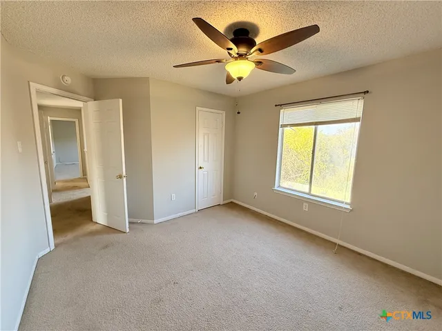 an empty room with a ceiling fan and window