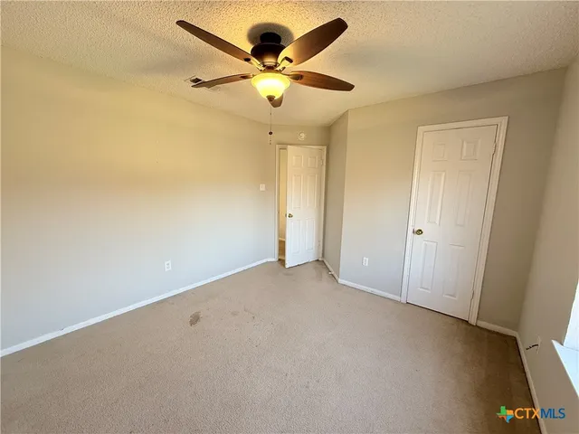 an empty room with a ceiling fan and a window