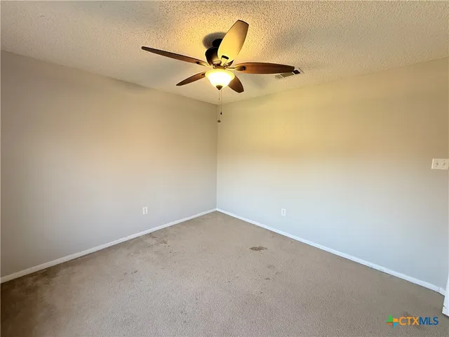 an empty room with a ceiling fan and a window