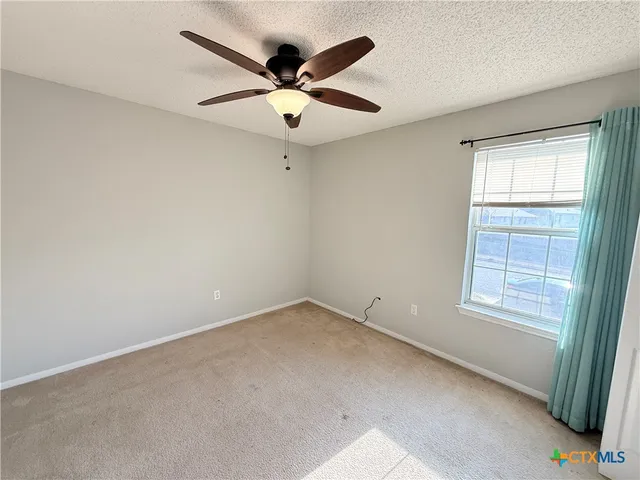 an empty room with a window and a fan