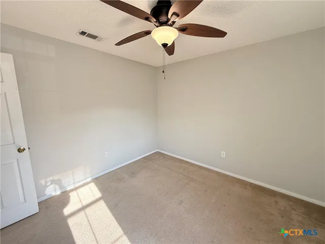 an empty room with a window and a fan