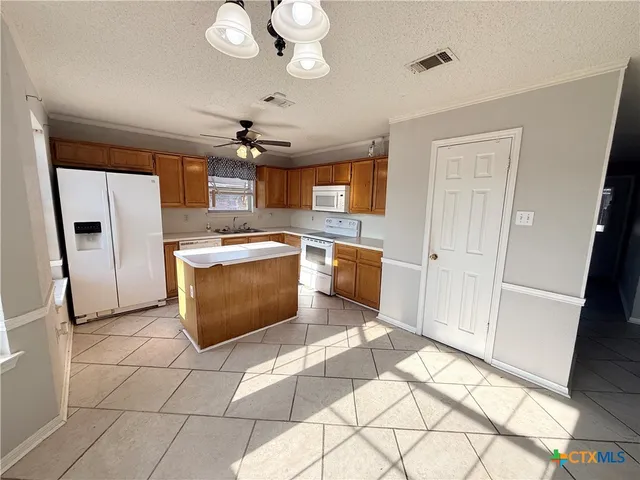 a kitchen with stainless steel appliances granite countertop a sink a stove a refrigerator cabinets and living room view