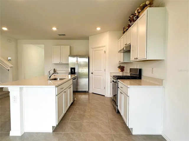 a large kitchen with stainless steel appliances lots of counter space and a sink