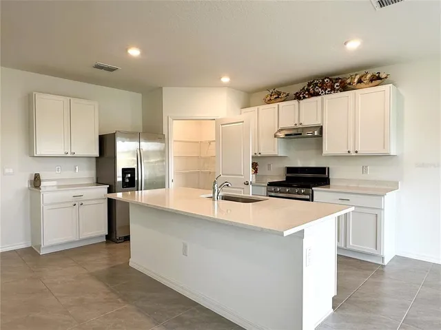 a kitchen with stainless steel appliances a sink a stove a refrigerator cabinets and a window