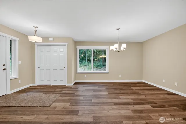an empty room with wooden floor cabinet and windows