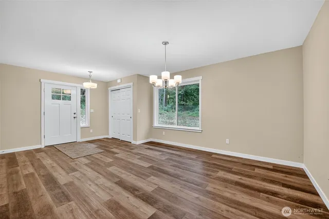 a view of an empty room with window and chandelier fan