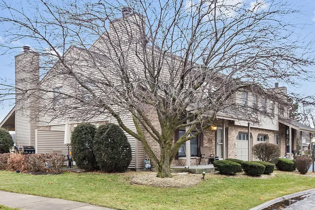 a front view of a house with garden and trees